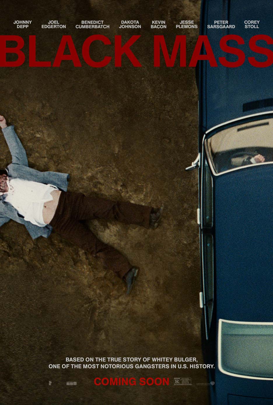 A man lying unconscious on the ground beside a black car.