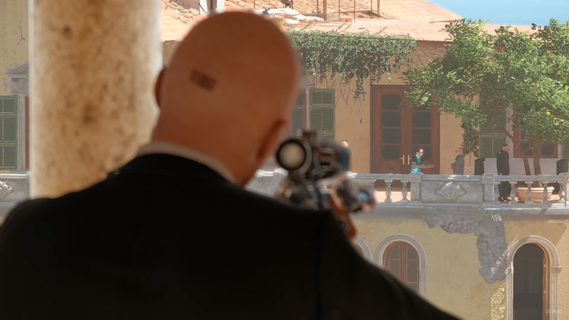 A hitman in a suit is holding a gun in front of a building.