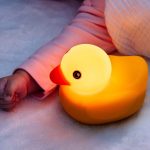 Edwin The Duck, a yellow duck light, is next to a baby.