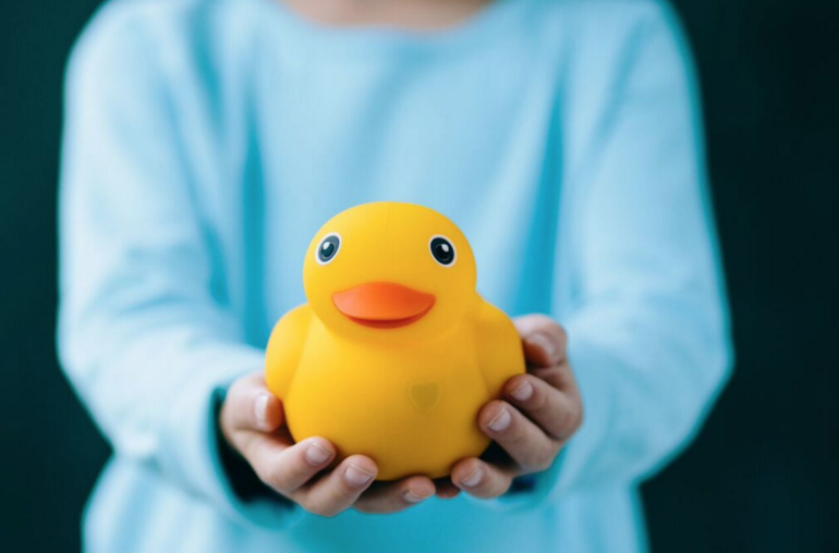 A child is holding a rubber duck toy called Edwin The Duck.