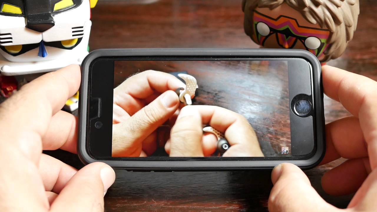 A person taking a picture of an iPhone 7 with a toy on it.