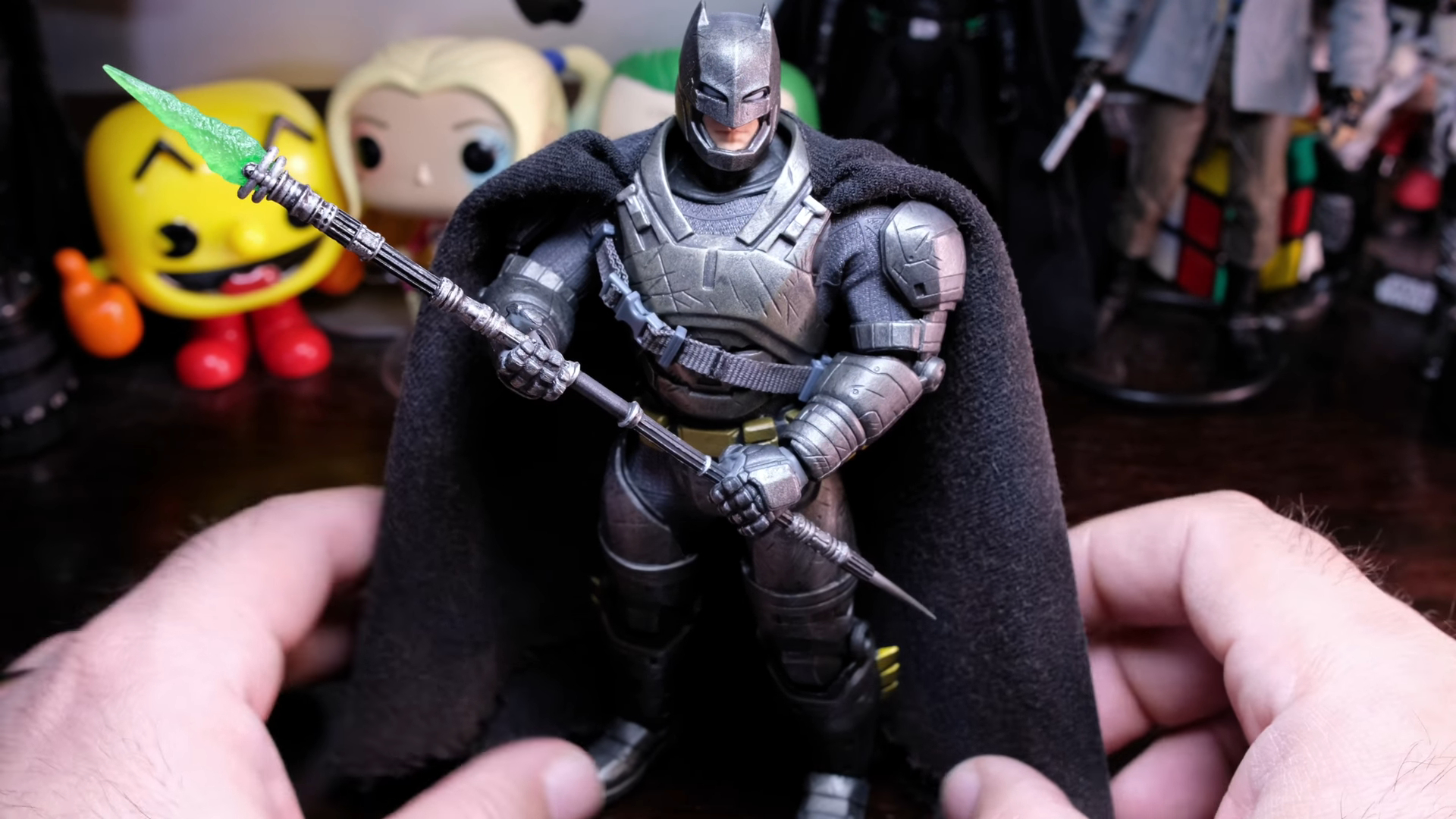 A hand holding a Batman action figure from the MEZCO Toyz One:12 Collective line for a JVB Reviews video.