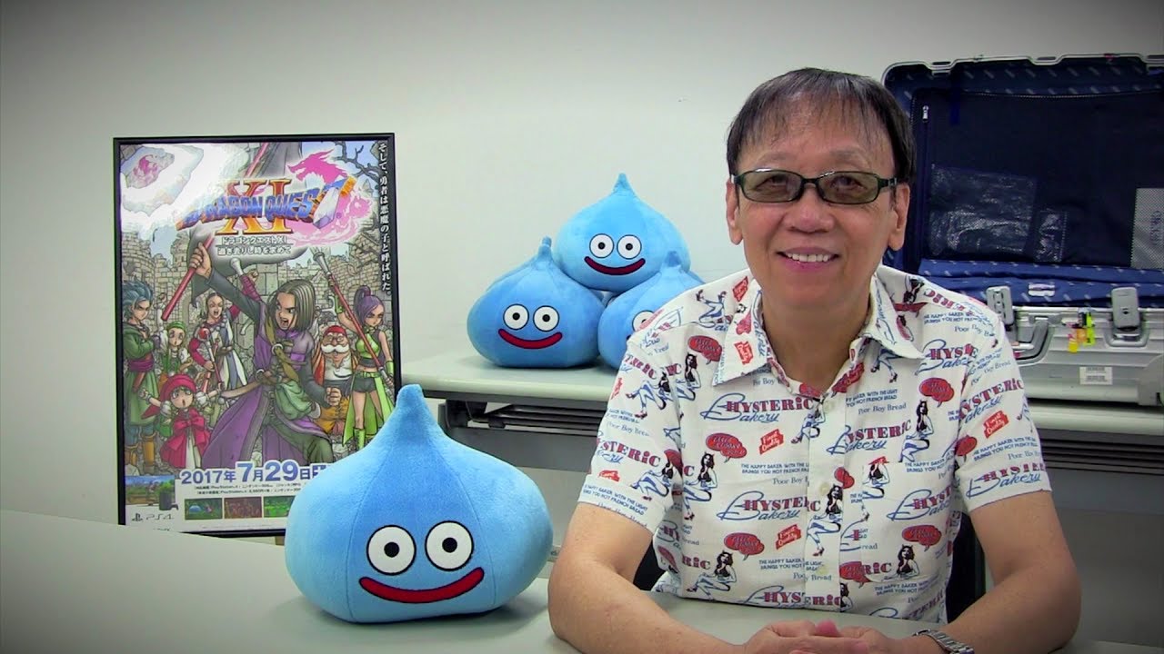 A man sitting in front of a table filled with several stuffed toys from Dragon Quest XI: Echoes of an Elusive Age.