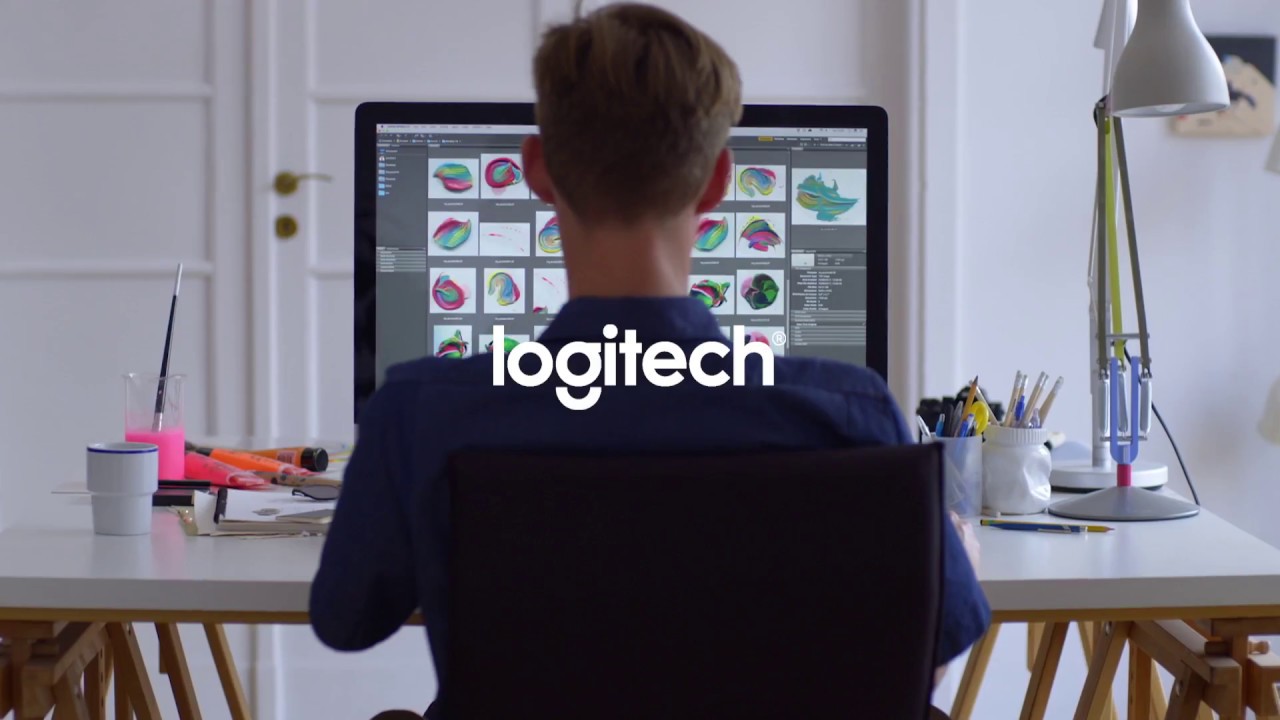 A man sitting at a desk in front of a computer with Logitech.