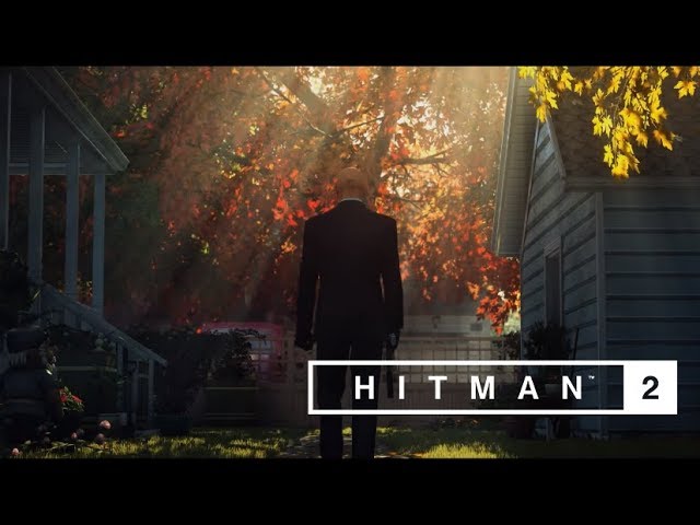 In the untouchable trailer for HITMAN 2, a man in a suit is standing in front of a house.