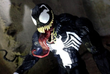 A Diamond Select Venom action figure is standing in a dark room.