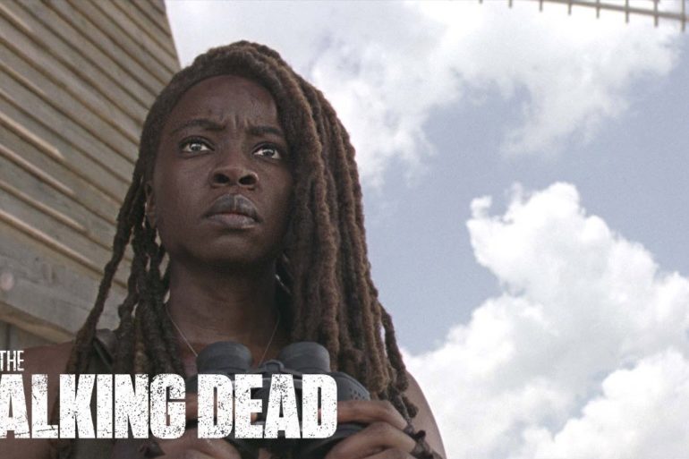 The Walking Dead Season 10 - a woman with dreadlocks in front of a building.