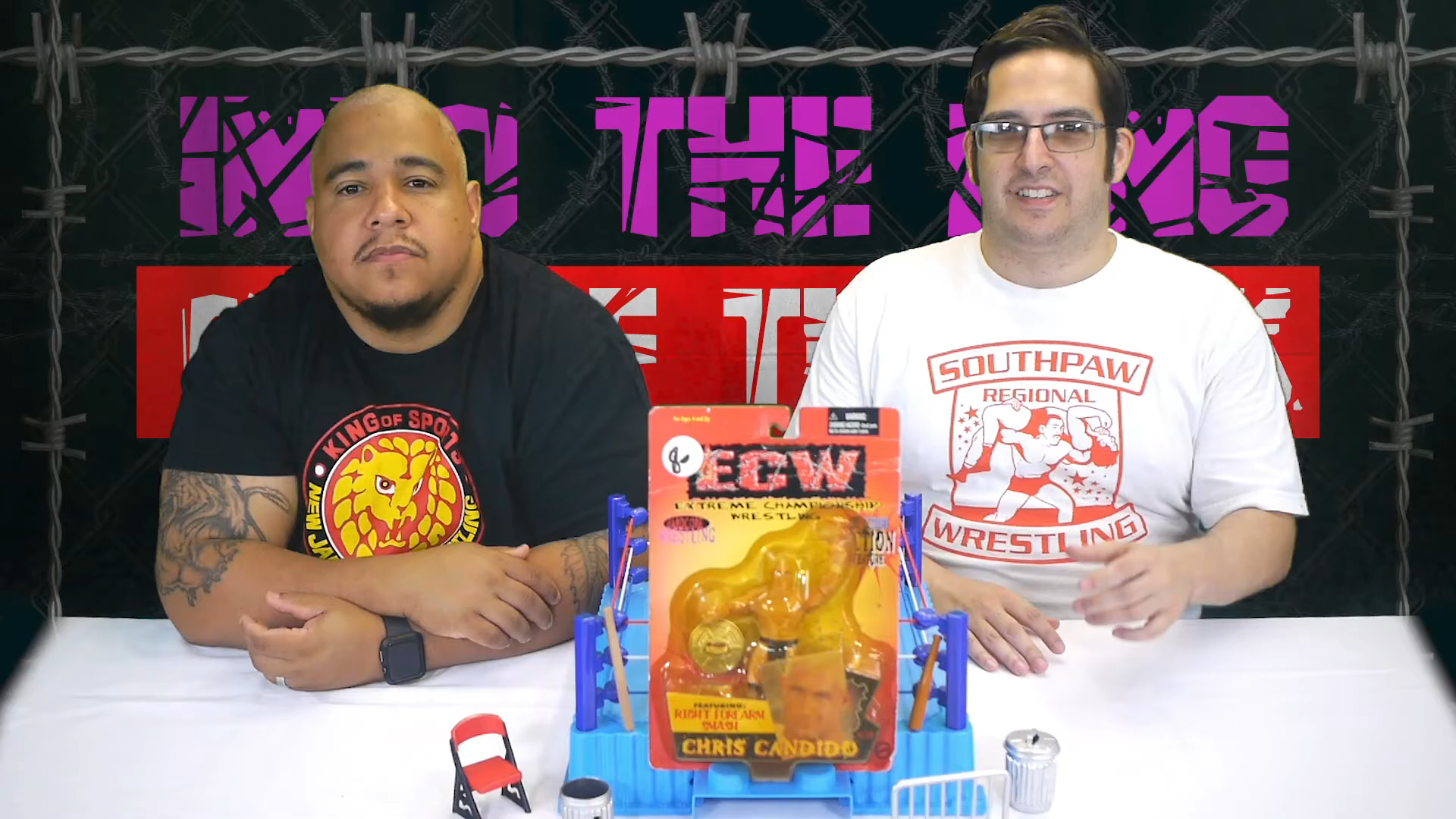 Two men, ECW Chris Candido and NN2D Retro Review, are sitting at a table with an action figure toy box in front of them.