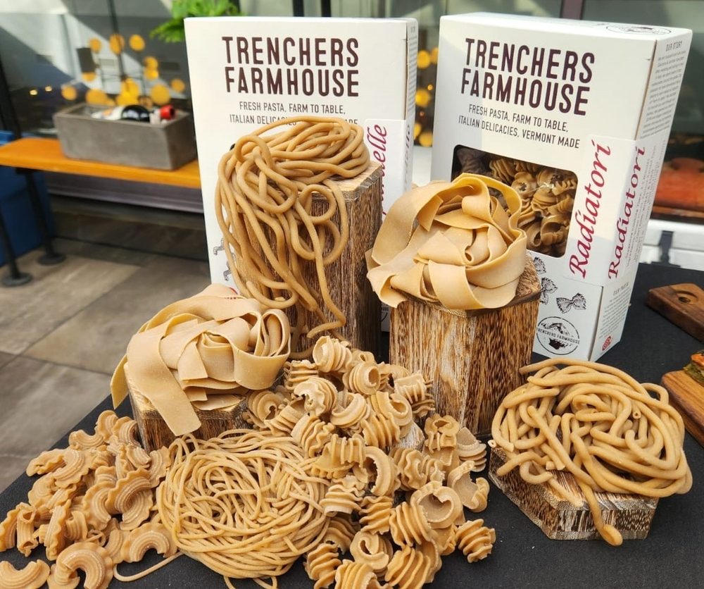 Boxes of Trenchers Farmhouse pasta are displayed with various pasta shapes arranged in wooden holders, perfect for inclusion in a Holiday Food Gift Guide.