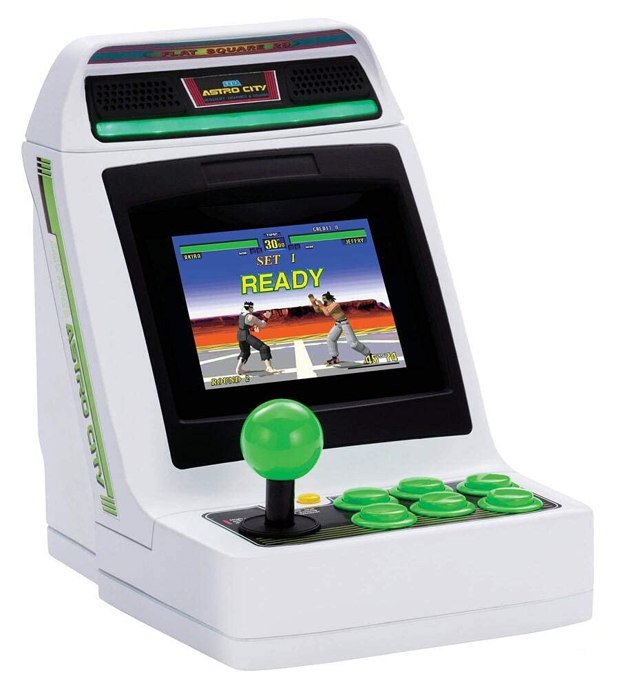 A small retro arcade machine, featured in the 2024 Holiday Tech Gift Guide by RAGE Works, boasts a green joystick and buttons while showcasing a thrilling fighting game on its screen.